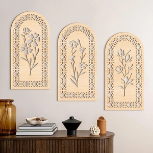 Close-up of three arch-shaped wooden wall art pieces with laser-cut floral carvings