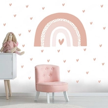 Detail of bohemian rainbow and heart wall decals in a cozy pink nursery setting