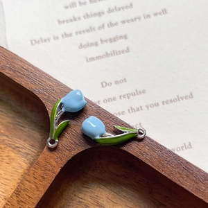 Close-up of light blue enamel tulip charms with green leaves on silver metal base