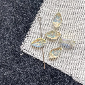 Macro shot of colorful iridescent glass leaf beads for DIY jewelry making and silver needle