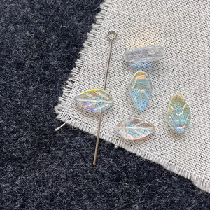 Detailed macro view of iridescent glass leaf beads with metallic pin for DIY jewelry making