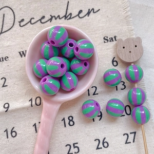 Macro detail of purple and green striped beads in a pink ceramic spoon for DIY crafts