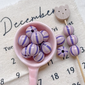 Close-up of purple striped resin round beads with central holes for DIY jewelry making