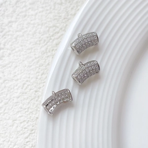 Macro view of three curved silver pendant tubes with micro-pave cubic zirconia settings