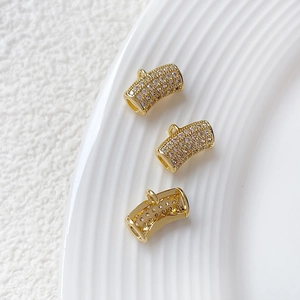 Macro view of gold curved tube pendant with micro-pave clear zircon for DIY jewelry