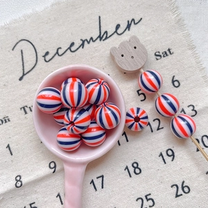 Detail of red and blue striped round beads on a ceramic spoon for DIY jewelry making