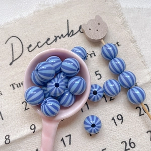 Macro shot of blue striped resin beads on a wooden pick for DIY jewelry making