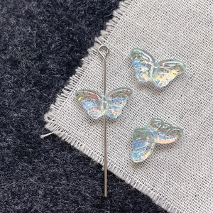 Iridescent glass butterfly beads for DIY jewelry making on textured fabric background