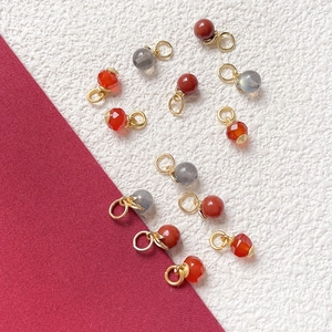 Detail of red agate and labradorite pendants with 18k gold plated metal charms