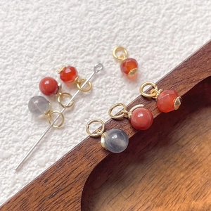 Handmade persimmon-style natural stone pendants with 18k gold plated loops on wood tray