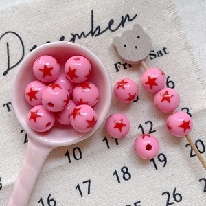 Close-up of pink acrylic round beads with red star print for DIY jewelry making