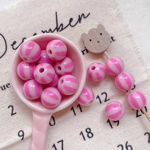 Close-up of pink striped circus style round acrylic beads for DIY jewelry making