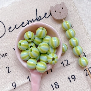 Detailed view of green and blue striped acrylic beads for DIY jewelry and phone charms