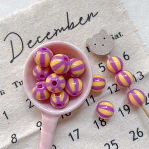 Detailed shot of striped colorful resin beads on a pink spoon for DIY craft projects