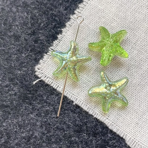 Detailed view of iridescent green glass starfish beads with metal pins for DIY jewelry