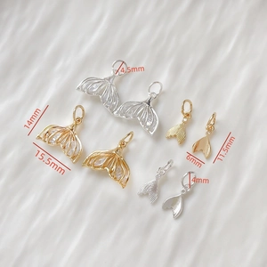 Macro shot of 14k gold-plated fish tail pendants with inlaid zircons in two sizes