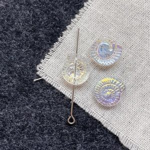Macro shot of iridescent glass nautilus shell beads for DIY jewelry with silver metal pin