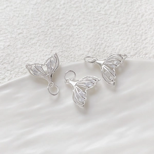 Macro detail of three silver hollow fishtail pendants with cubic zirconia for DIY jewelry