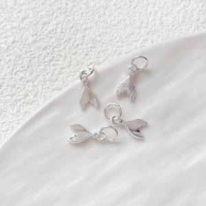 Close-up of four polished silver mermaid tail pendants for DIY jewelry making