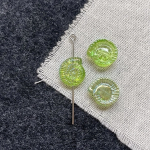 Macro detail of iridescent spiral glass beads for DIY jewelry with nautilus shell texture