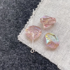 Close-up of pink iridescent shell beads with silver pins on a textured fabric background
