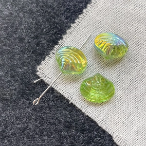 Close-up of iridescent green shell glass beads showing the hole and DIY assembly