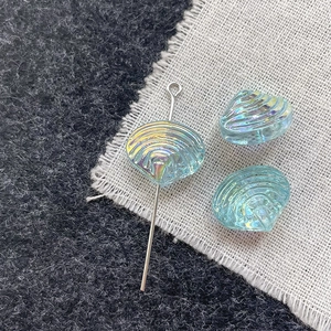 Macro shot of colorful shell-shaped glass beads with iridescent aurora finish and pins
