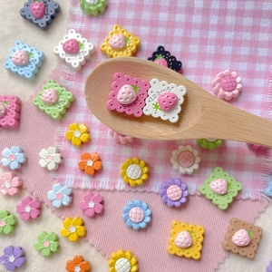 Colorful strawberry and flower DIY beads set displayed on a wooden spoon and checkered cloth