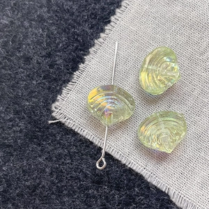 Detailed macro view of light green shell-textured glass beads with aurora AB coating for DIY
