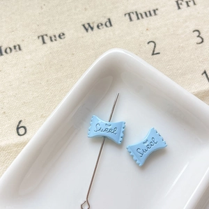 Vue macro d'une perle en résine bleu clair en forme de bonbon avec gravure Sweet pour bijoux