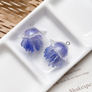 Dettaglio macro di ciondoli a forma di medusa in resina viola e bianca con glitter DIY