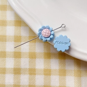 Macro shot of light blue enamel flower charm with pink center and silver pin
