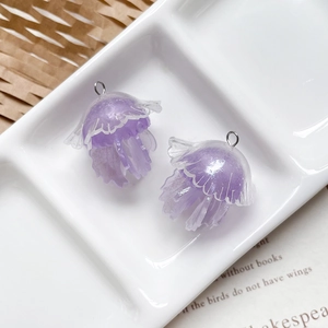 Dettaglio macro di ciondoli a forma di medusa in resina viola con glitter e anelli