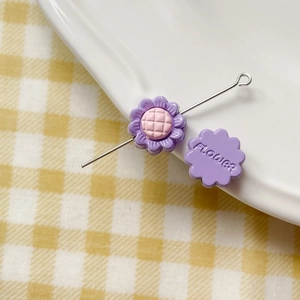Close-up of purple resin sunflower charms with flower engraving for DIY jewelry