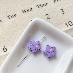 Vue macro de perles en étoile violettes avec motif Smile pour la création de bijoux DIY