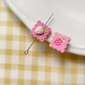 Macro shot of sweet pink biscuit charm with strawberry detail and metal pin for DIY jewelry