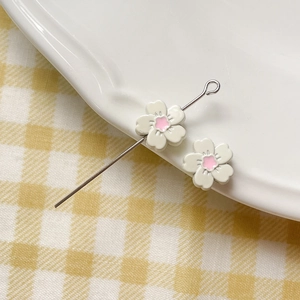 Macro shot of white flower beads with pink centers on a metal pin for DIY jewelry making