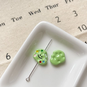 Vue macro de perles nuages vert pastel avec un smiley et un charme de palette de peintre