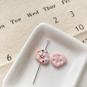 Détail d'une perle DIY en forme de nuage rose avec sourire sur un plat céramique