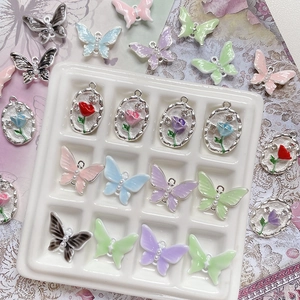 Dettaglio macro di ciondoli in lega con farfalle, rose, smalto colorato e perle fini
