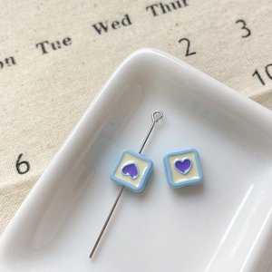 Macro de perles carrées bleues en alliage avec cœur violet et épingle argentée sur plateau