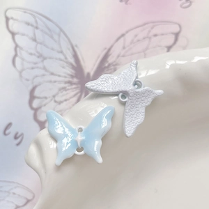 Dettaglio macro di ciondoli a farfalla blu e bianchi con anellini per gioielli DIY