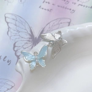Vista macro di ciondoli a farfalla blu con perle e charms in metallo argento satinato
