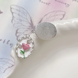 Dettaglio dei ciondoli ovali a rosa con smalto bianco e retro in argento testurizzato