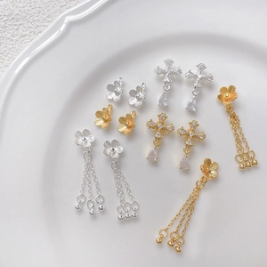 Macro shot of gold-plated flower earrings with cross pendants and zircon beads