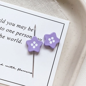 Macro shot of purple star button beads with four white center dots for jewelry making