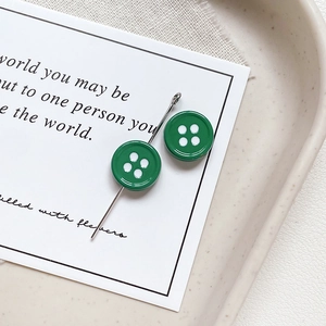 Close-up of green button-shaped star charms with vintage alloy finish on a ceramic tray