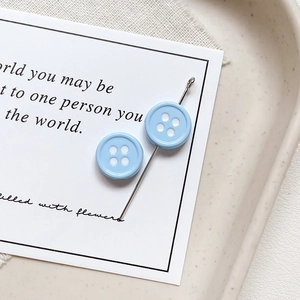 Detailed macro shot of light blue button-shaped charms on a vintage poetry card