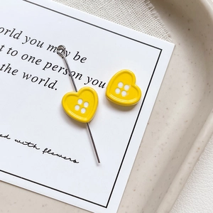 Macro shot of yellow heart button charms with needle pin for DIY jewelry making