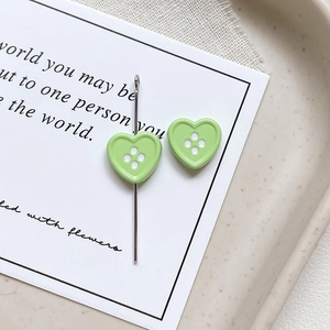 Close-up of heart-shaped four-hole buttons in green lacquer finish for DIY jewelry crafts